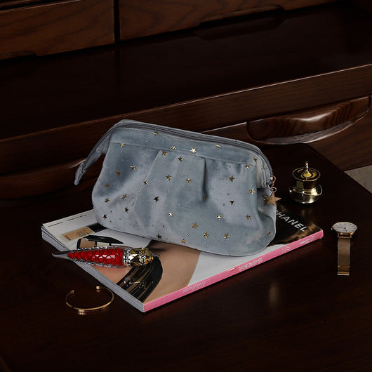 akhi washable beauty product case grey velvet makeup pouch with gold star studs zipper charm on dark wood dresser