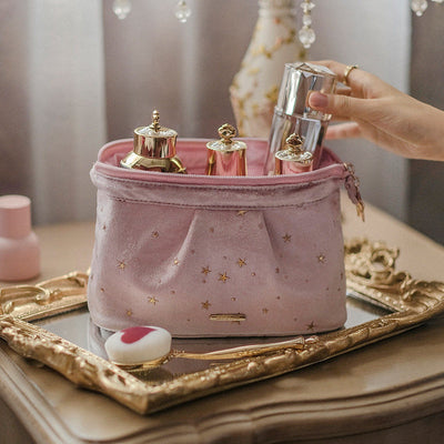 Pink velvet star print washable beauty product case on ornate mirrored tray holding perfume bottles